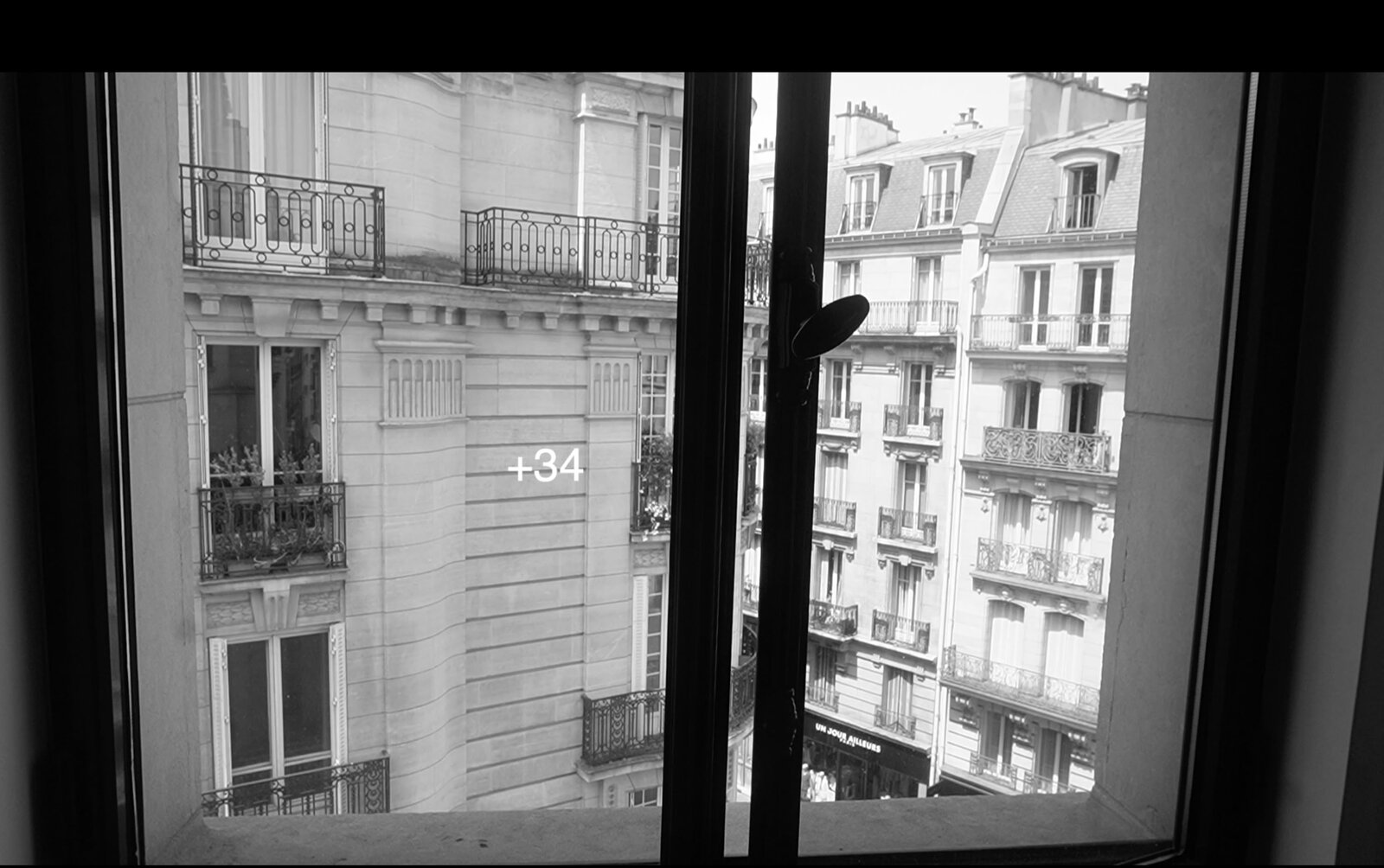 Submission Canicule still — Paris rooftops seen through a window, black and white