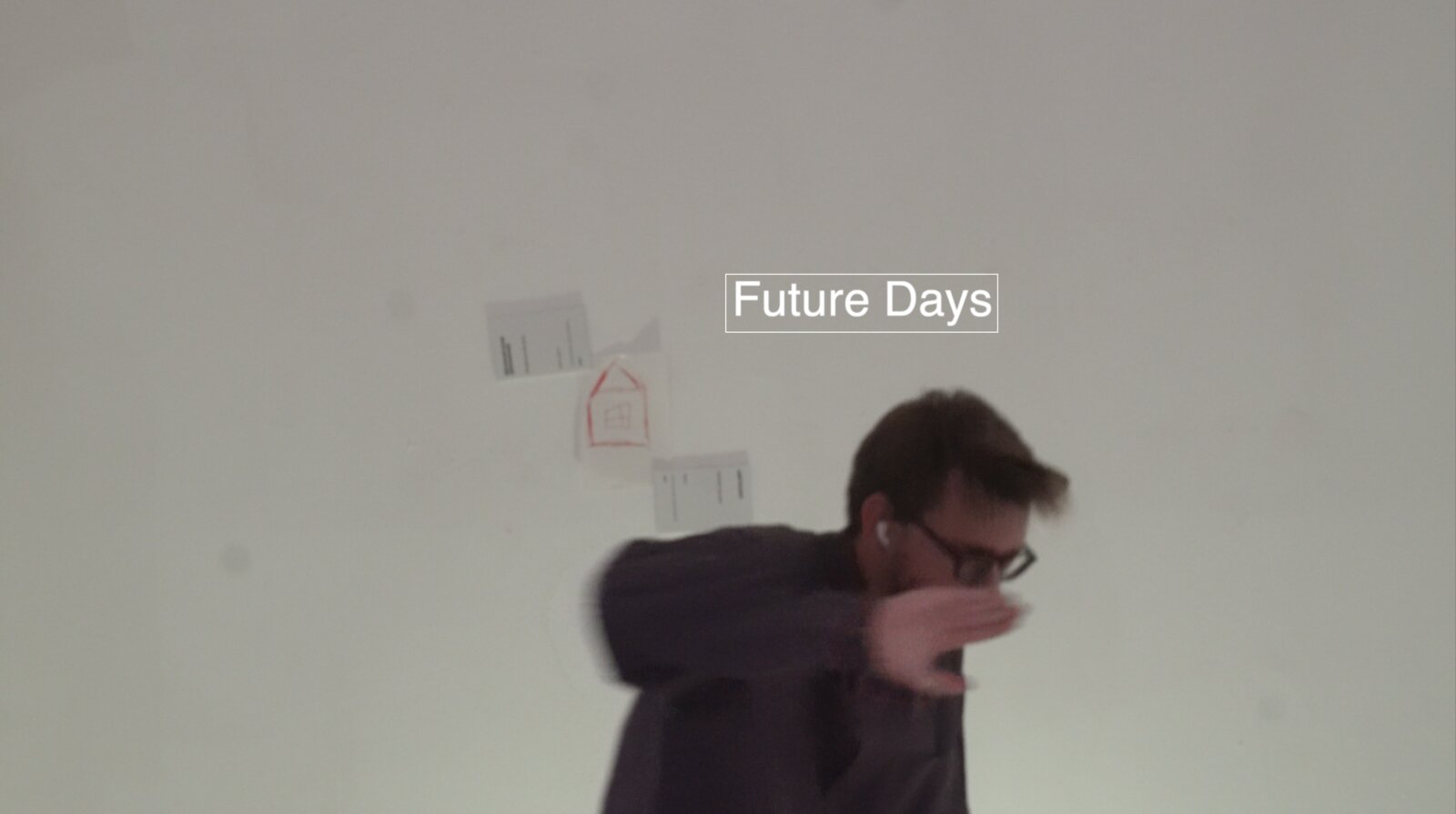 Future Days still — a man mid-motion in front of a wall with a child's drawing of a house