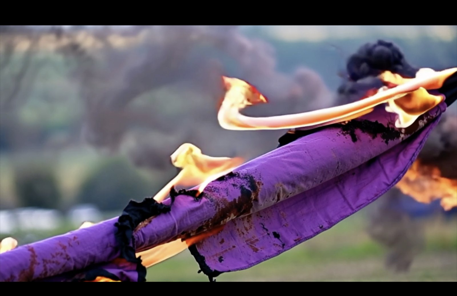 Trilogy of Letters and Territories still — burning purple fabric close-up
